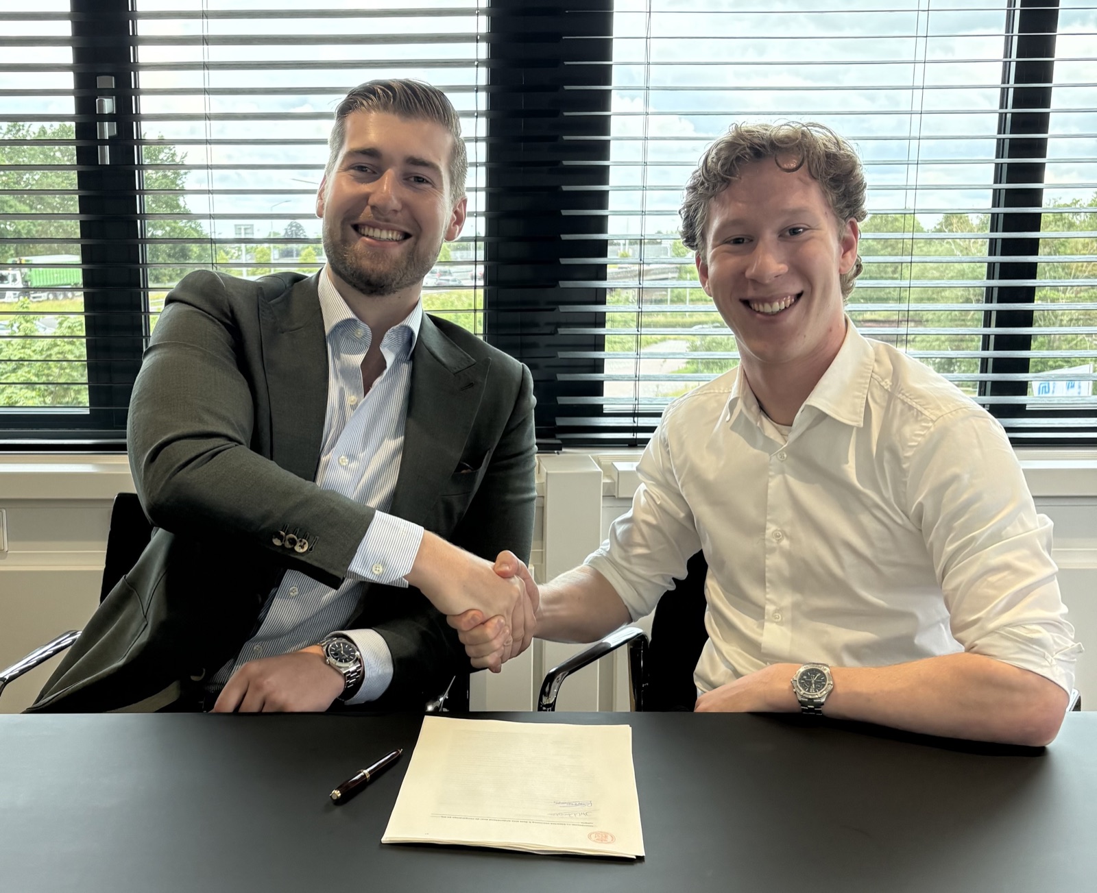 Rik Smeets and Justin van Dongen shaking hands over the signed deed founding JKC Software B.V.